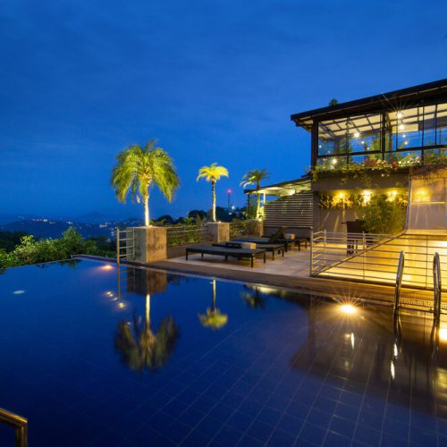 Night time view of Infinity pool, sunloungers and restaurant